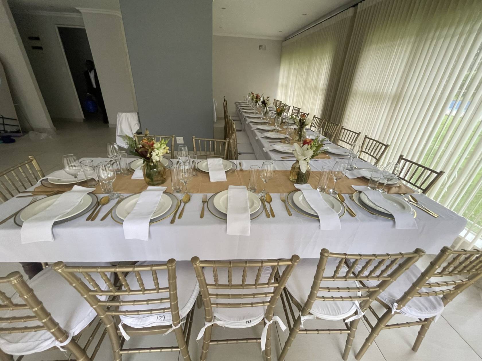 Long dining table set with white linens and gold chairs