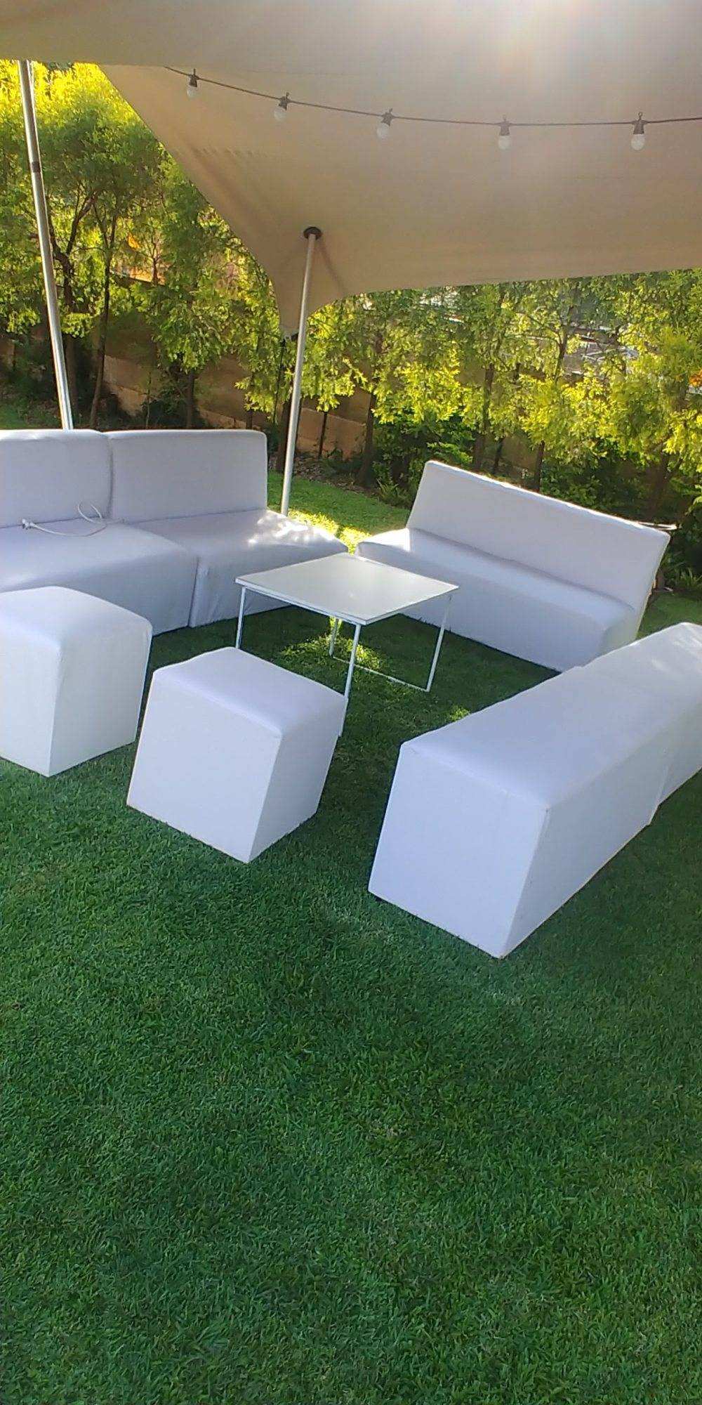 White lounge furniture setup on grass under a canopy