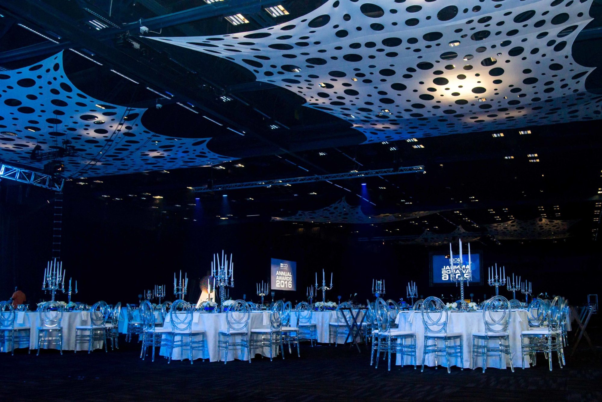 Tables set for a formal event with blue decor and centerpieces.