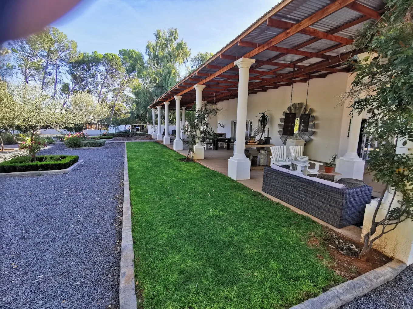 Garden area with grass and covered patio beside a chapel.