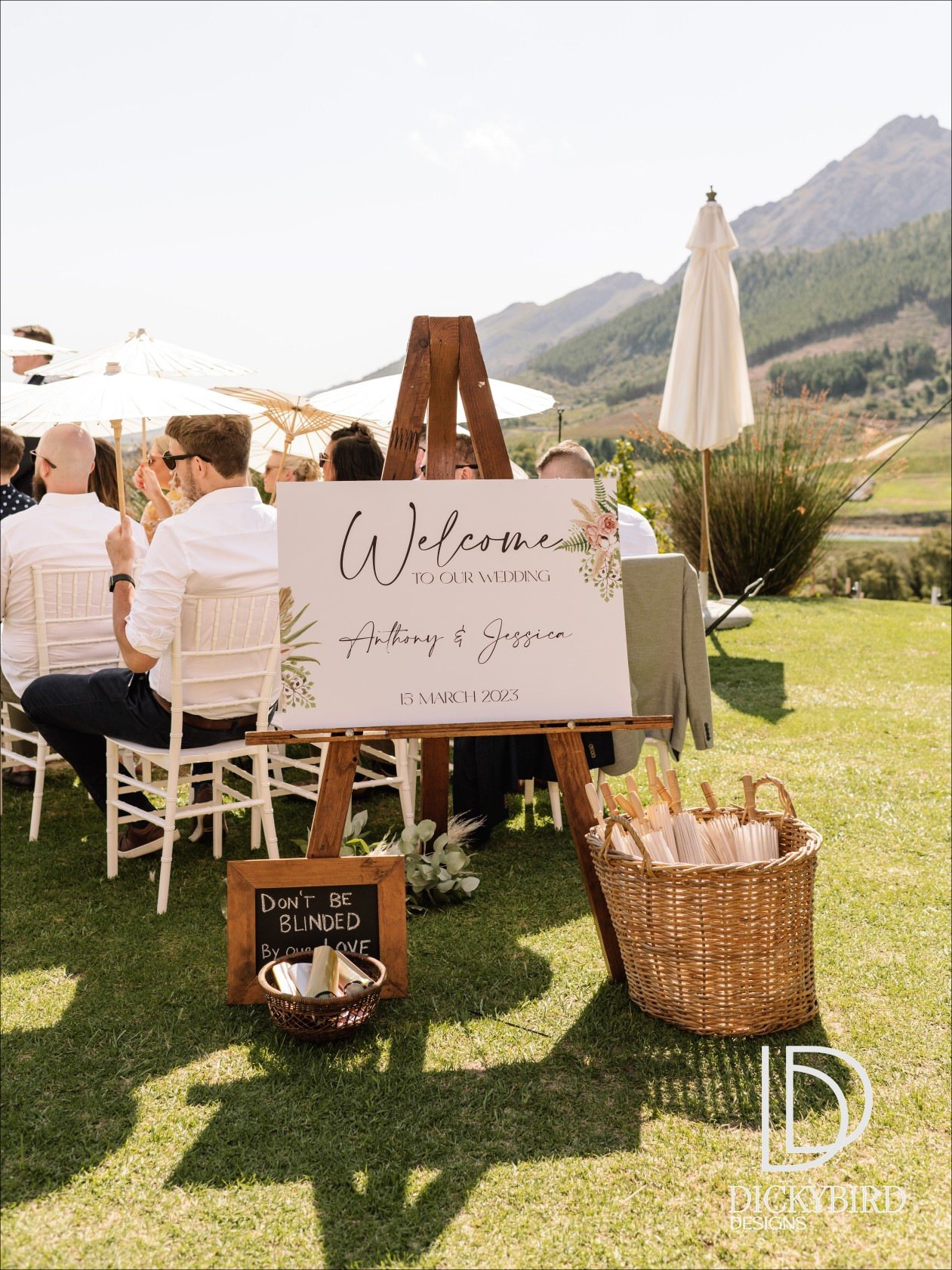 Wedding welcome sign with floral design on an easel in a garden setting.
