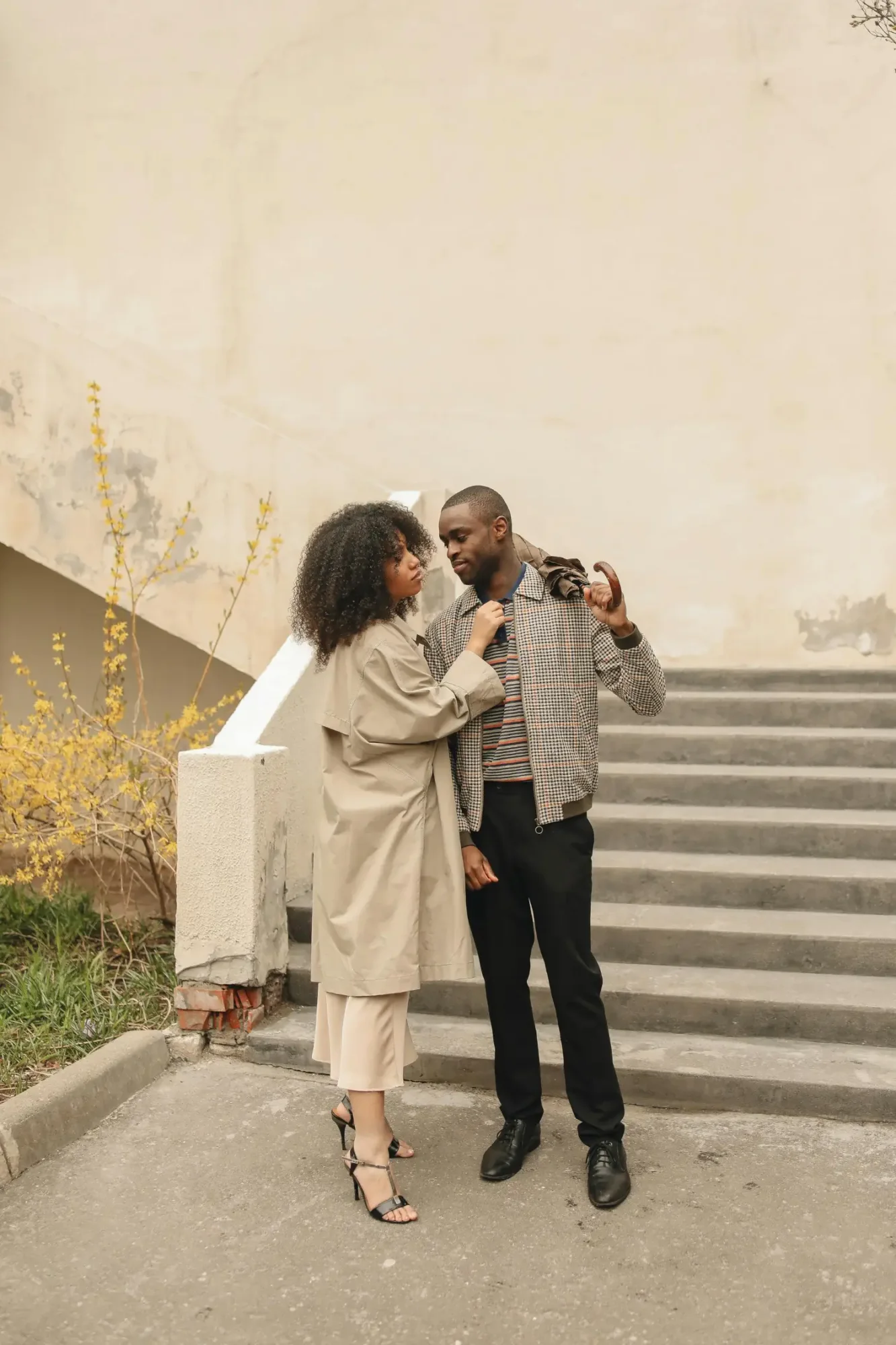 Couple standing on stairs, engaging with each other.