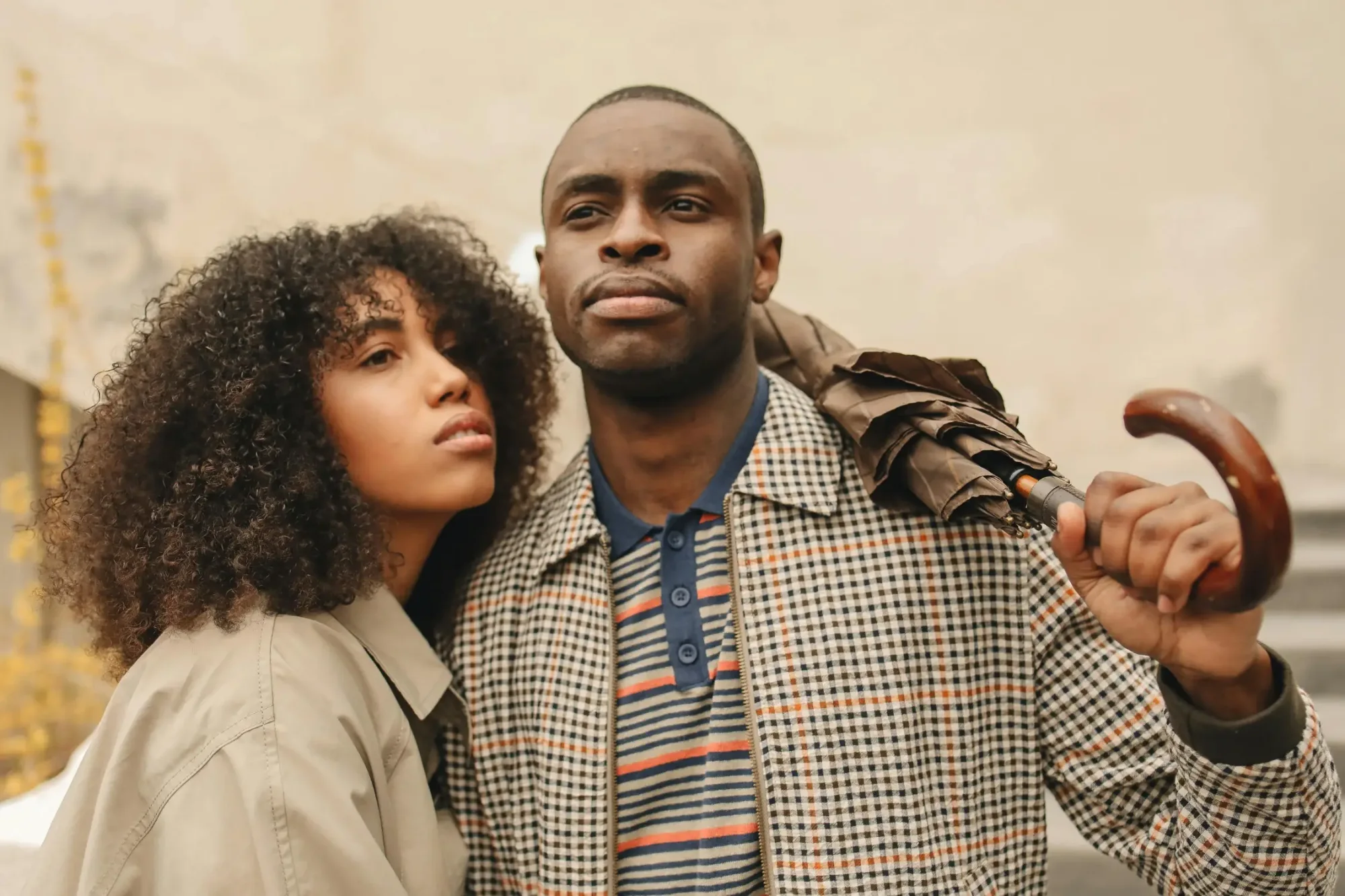 Couple posing outdoors, man holding umbrella.