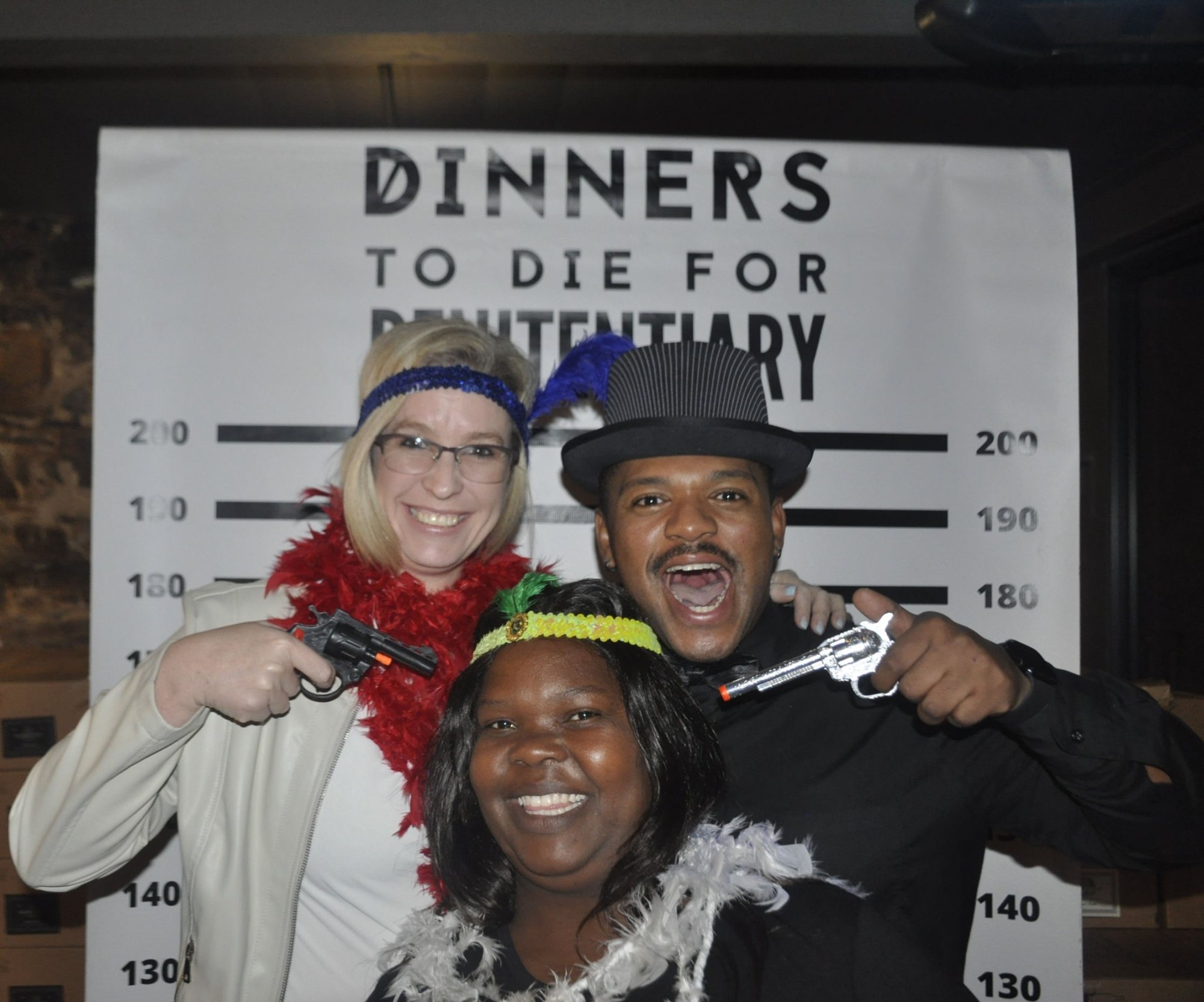 Participants in themed costumes pose with props at a murder mystery event.