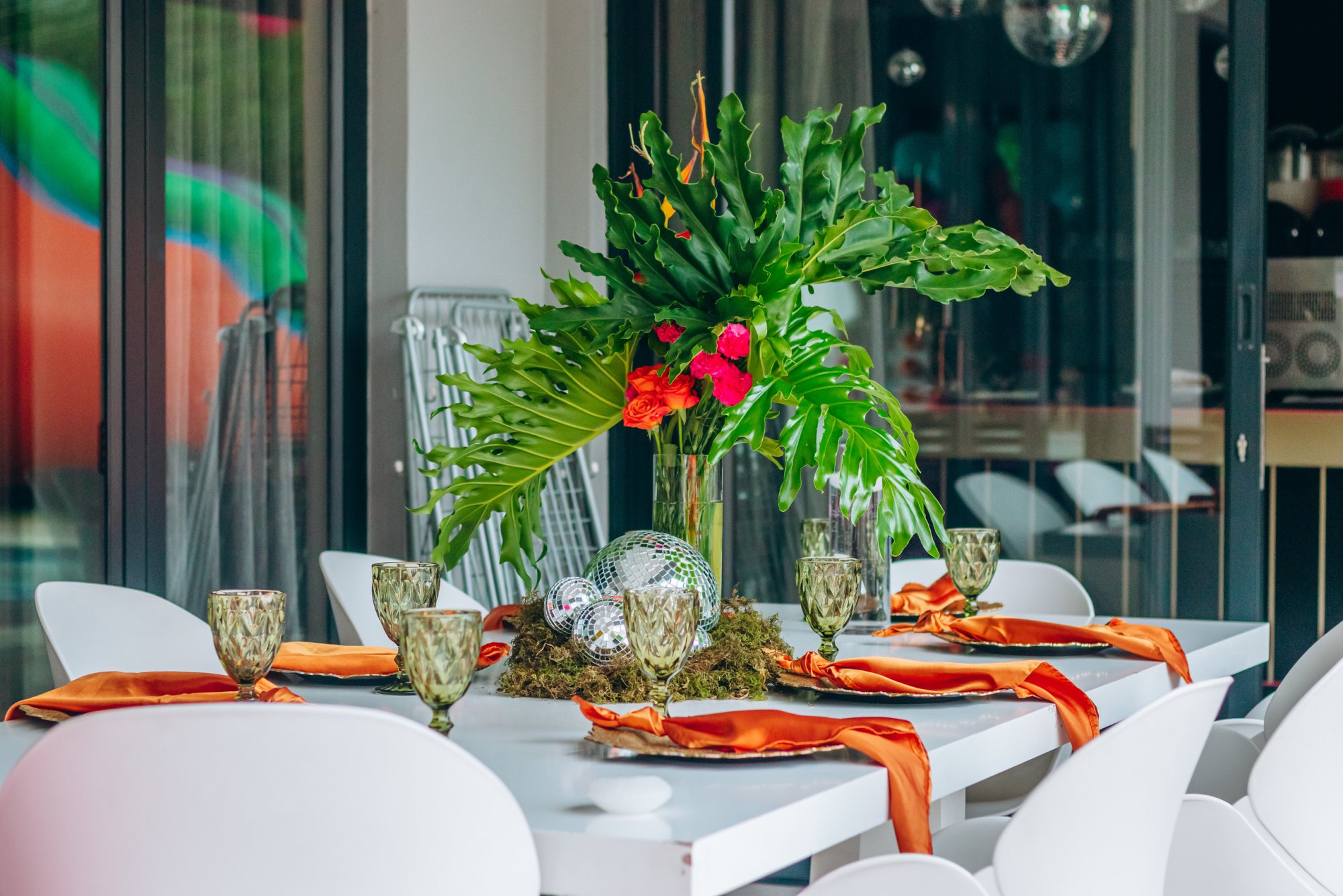 Table decorated with flowers, greenery, and glassware.