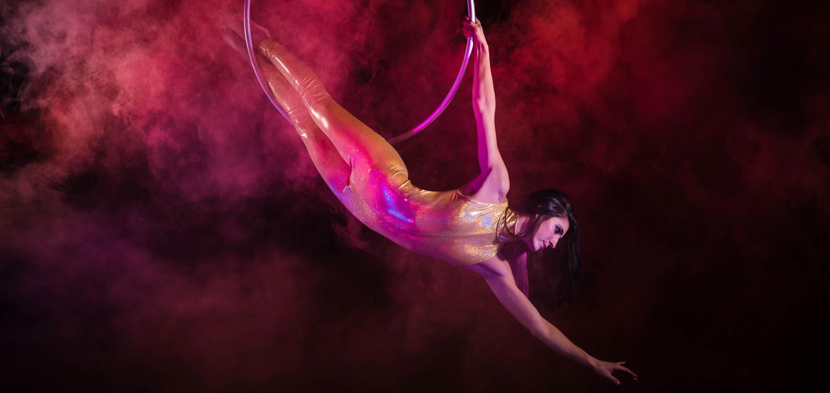 Aerialist performing with a hoop in colorful smoke