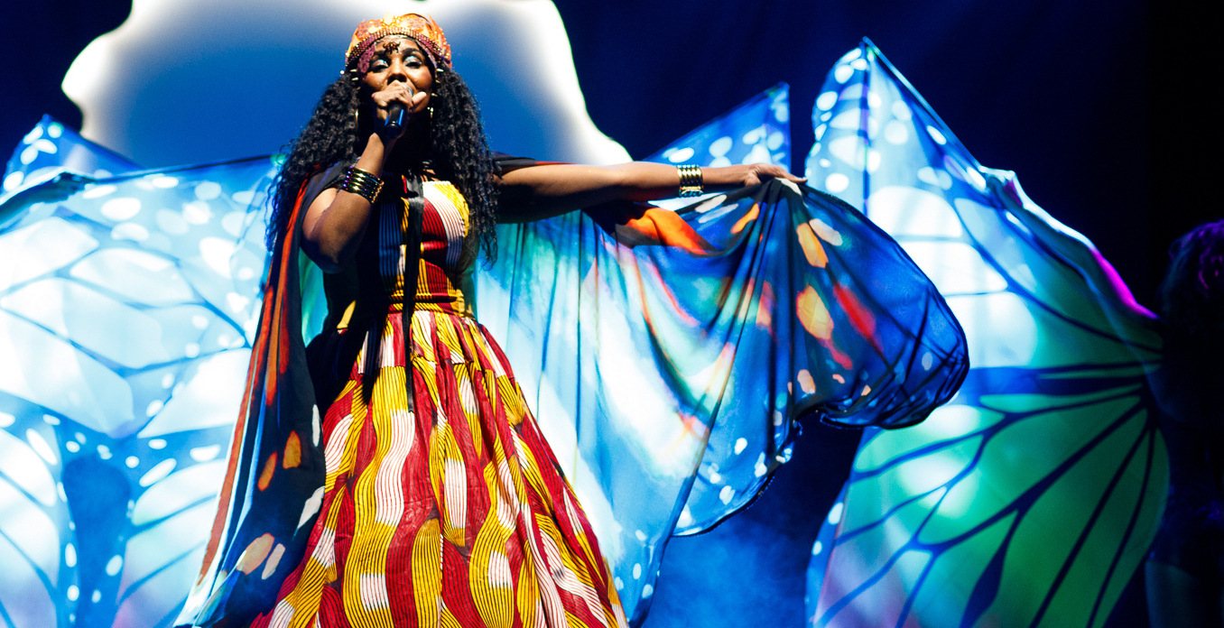 A performer in colorful attire singing on stage.