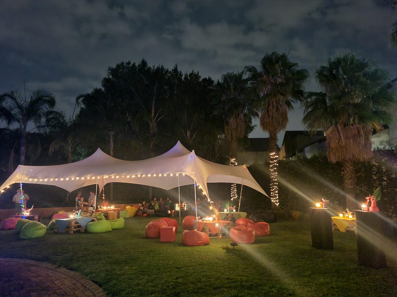 Outdoor tent setup with colorful seating and lights at night