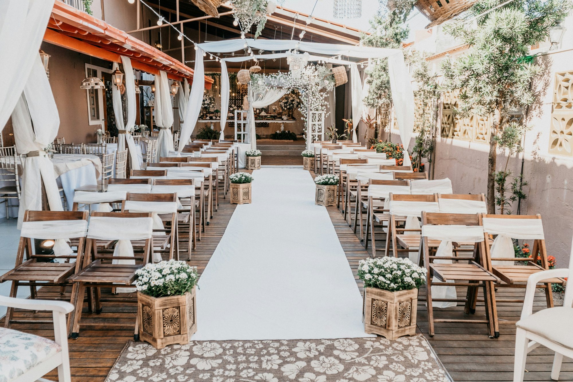 Outdoor ceremony setup with wooden chairs and floral arrangements