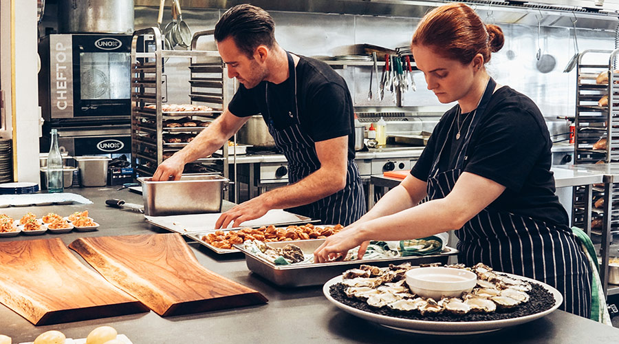 Two chefs preparing food in a professional kitchen