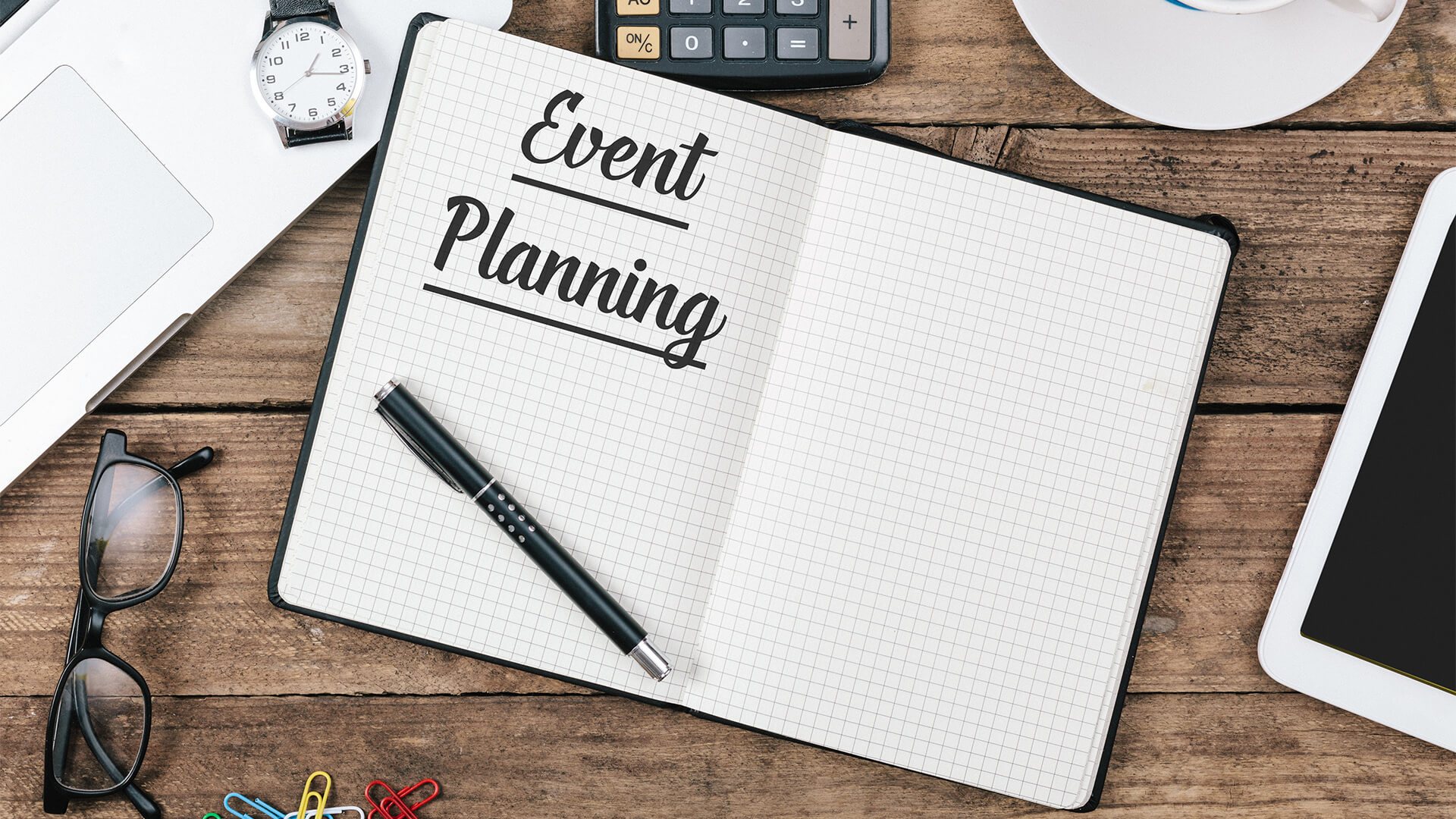 Notebook with 'Event Planning' written on the cover and office supplies