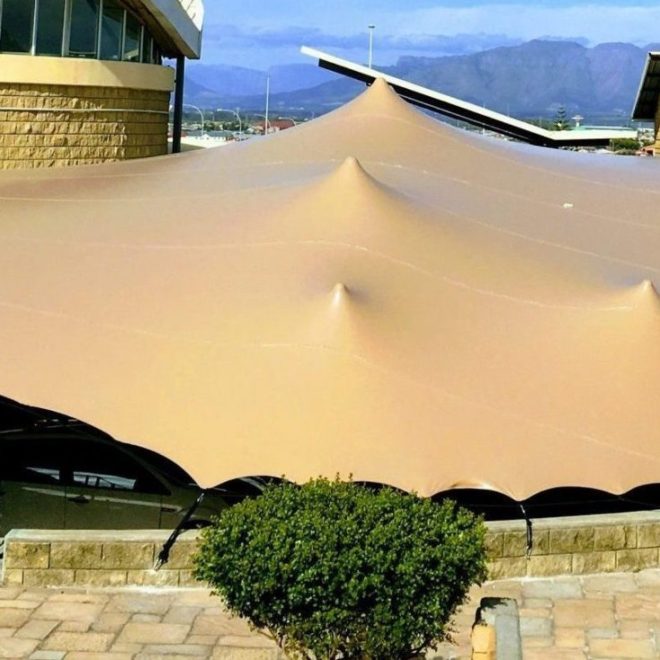 Large beige stretch tent set up in an outdoor venue.