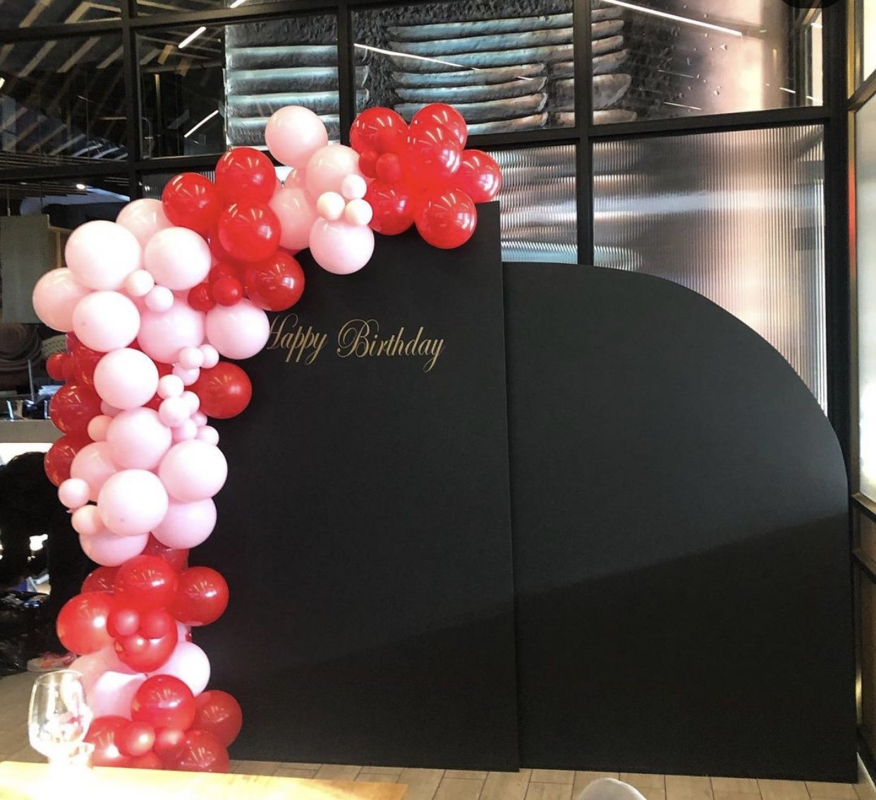 Black birthday backdrop with red and pink balloon arch