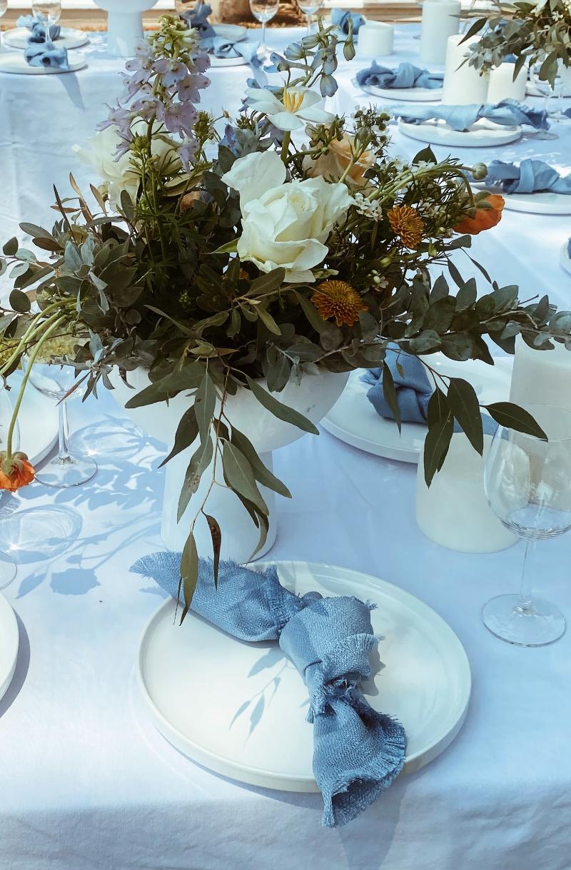 Floral centerpieces on a table with blue napkins