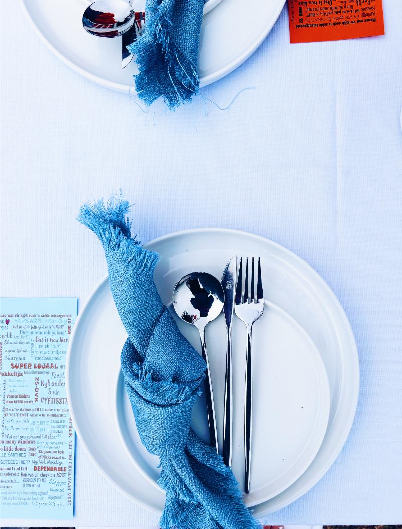 Stylishly set dining table with white plates and blue napkins