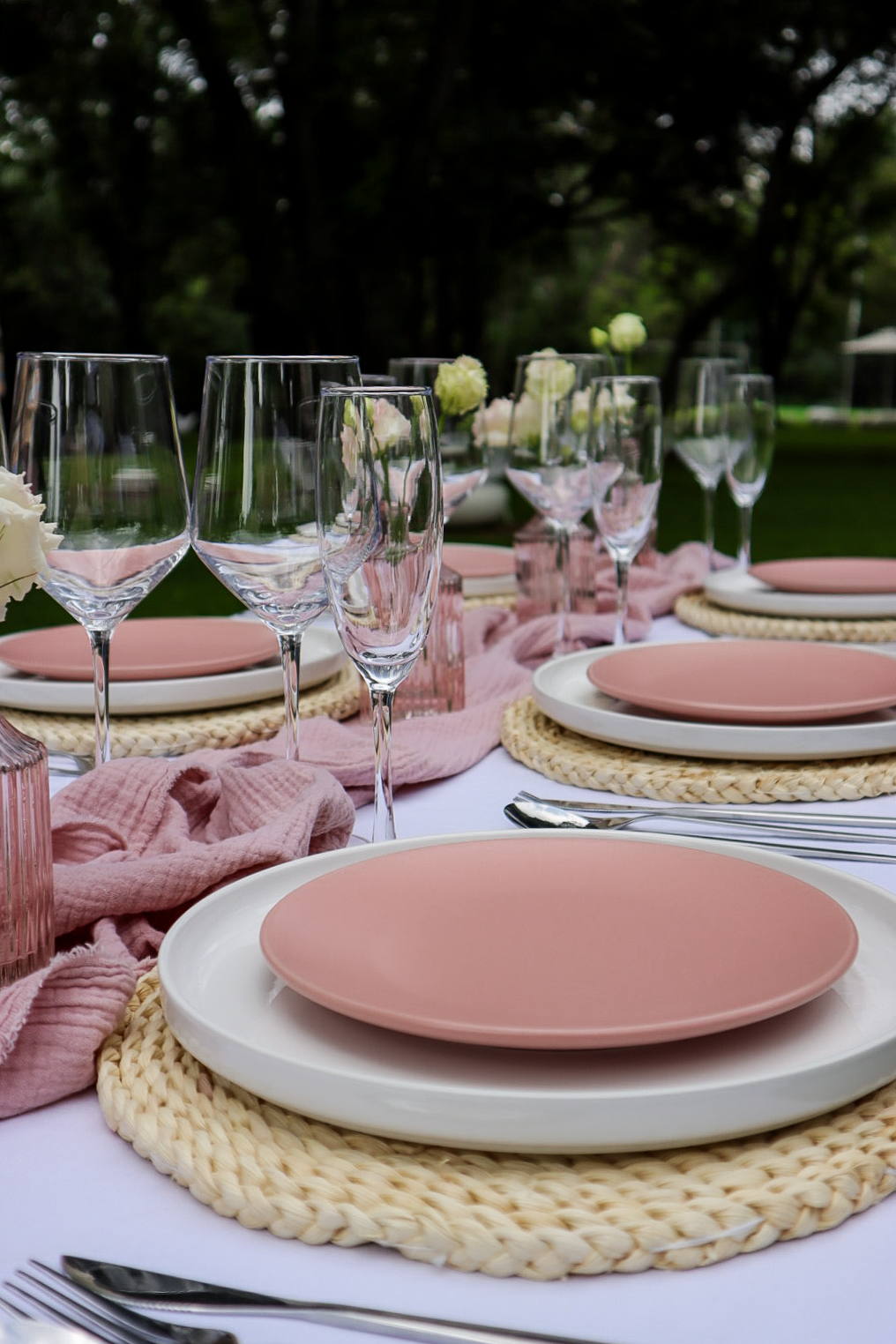 Decorated outdoor table with pink plates and glassware