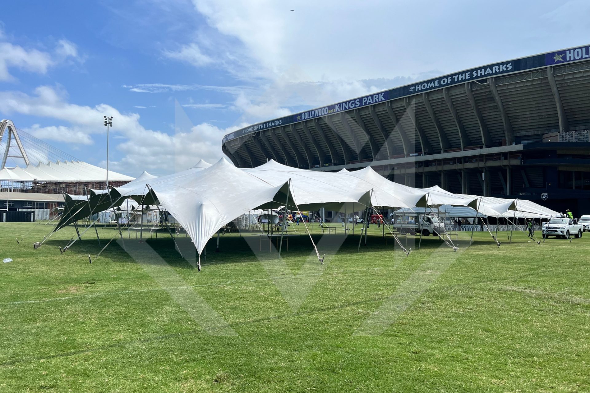 Large stretch tent set up on grassy field near sports stadium