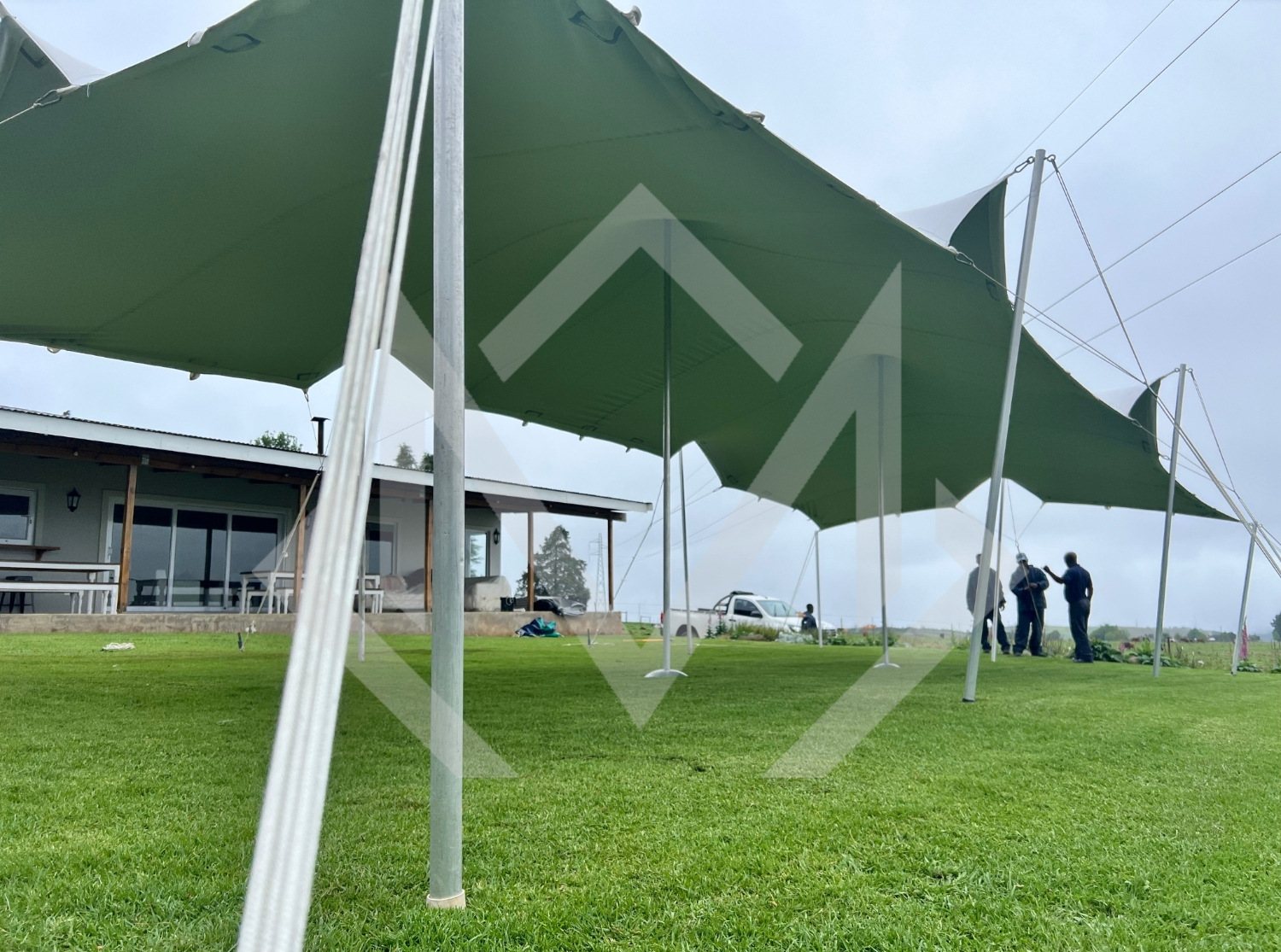 Green Bedouin stretch tent being set up on grass