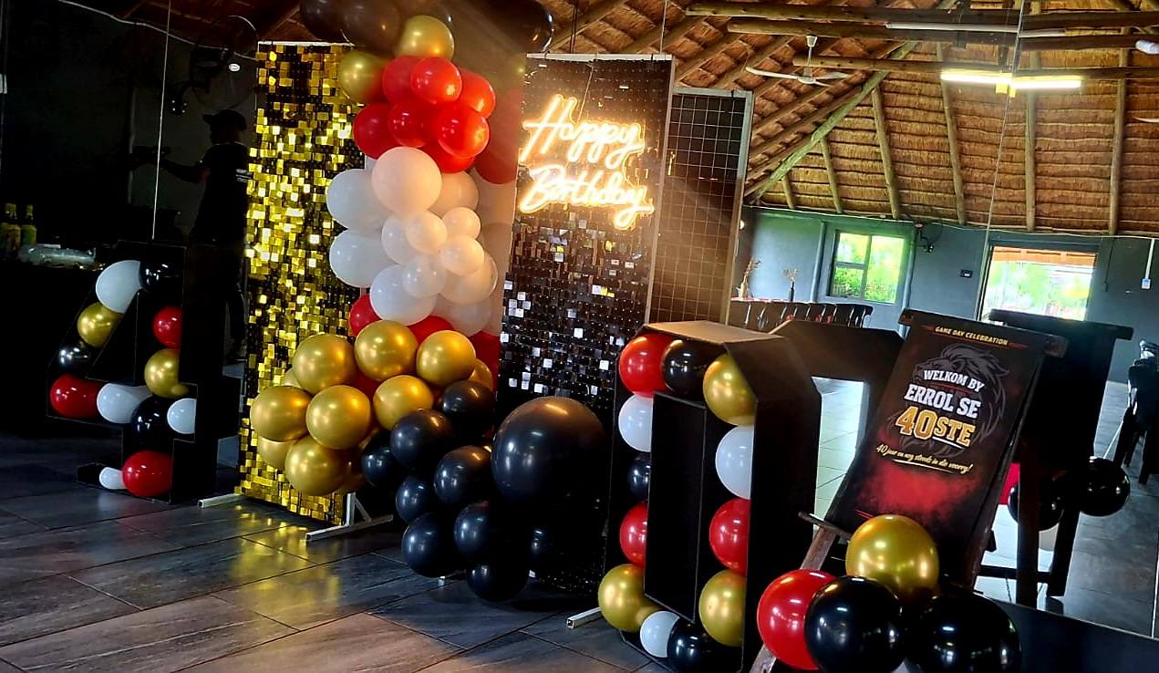 Colorful birthday party setup with balloons and neon sign.