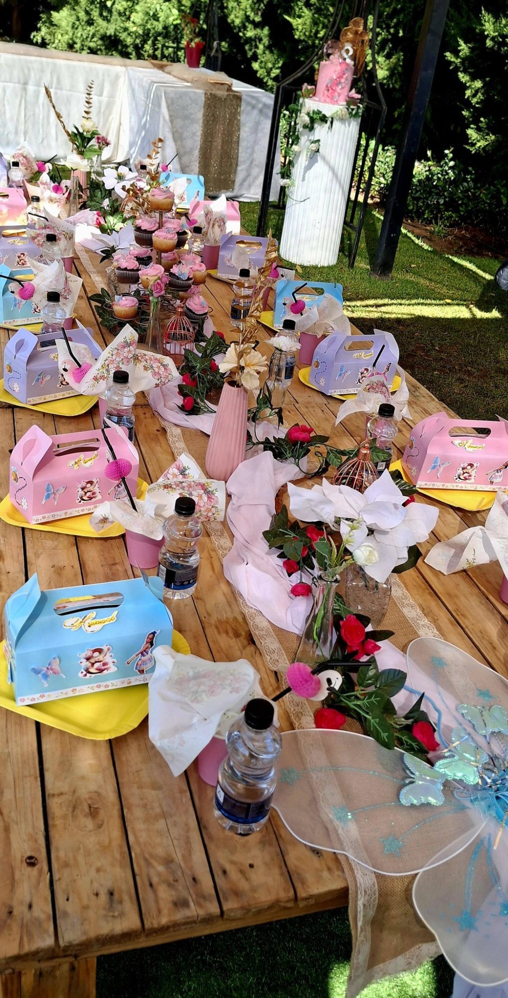 Decorated table with cupcakes, floral arrangements, and themed boxes