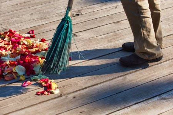 Person sweeping flower petals off a wooden floor