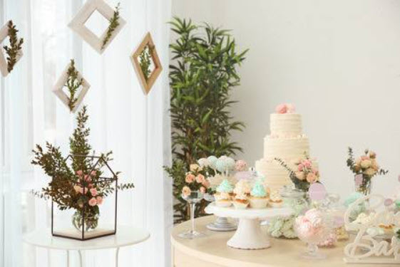 Dessert table with cake, cupcakes, and floral decor.