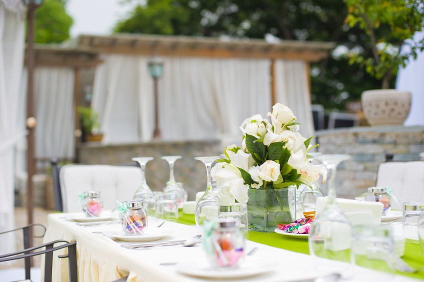 Outdoor table setting with floral centerpiece and glassware.