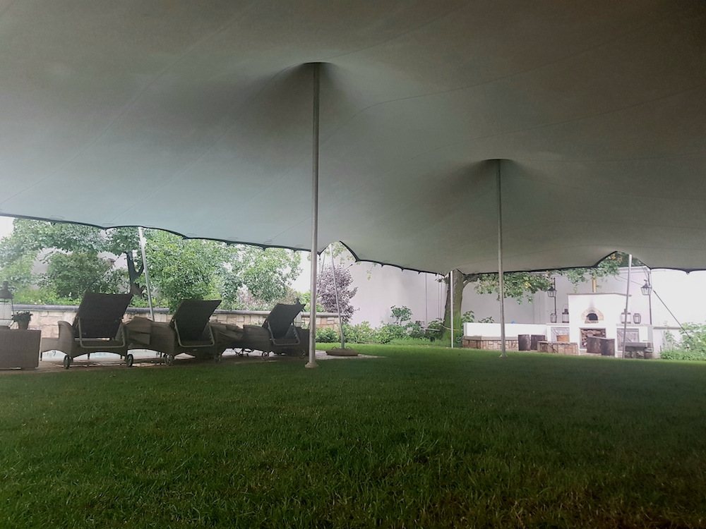 Large stretch tent setup on grass with seating