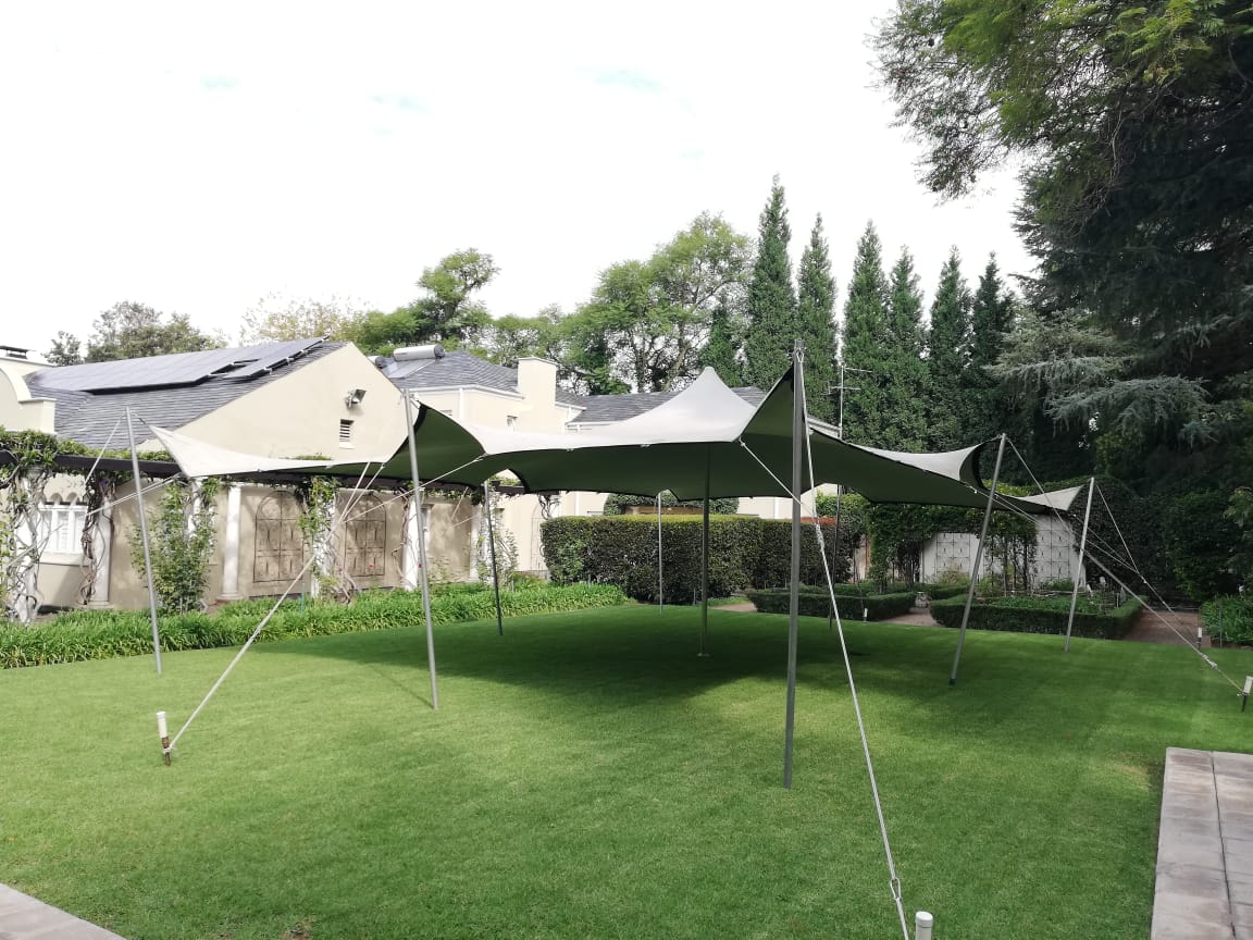 Stretch tent setup on a grassy area behind a building