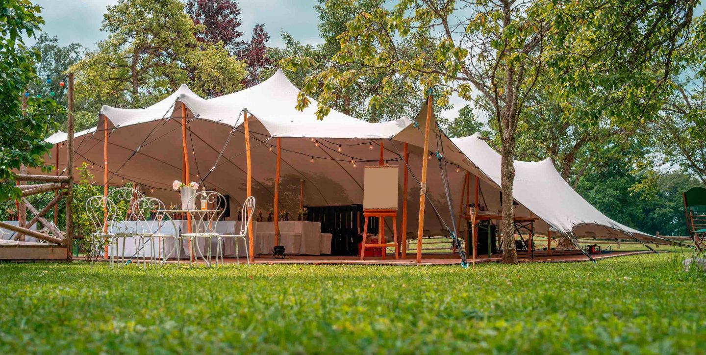 Stretch tent setup with tables and chairs on grass