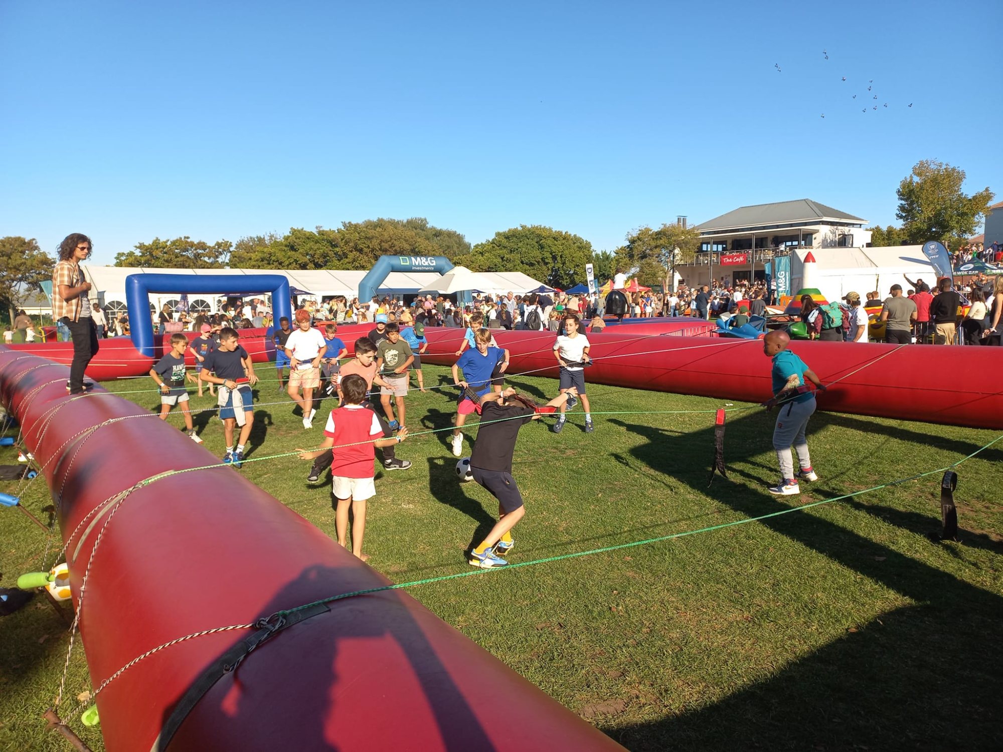 Participants enjoying a game of Giant Human Foosball on a sunny day