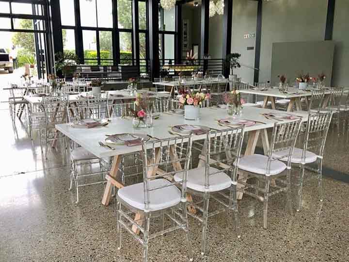 Neatly arranged dining tables with clear chairs and floral centerpieces