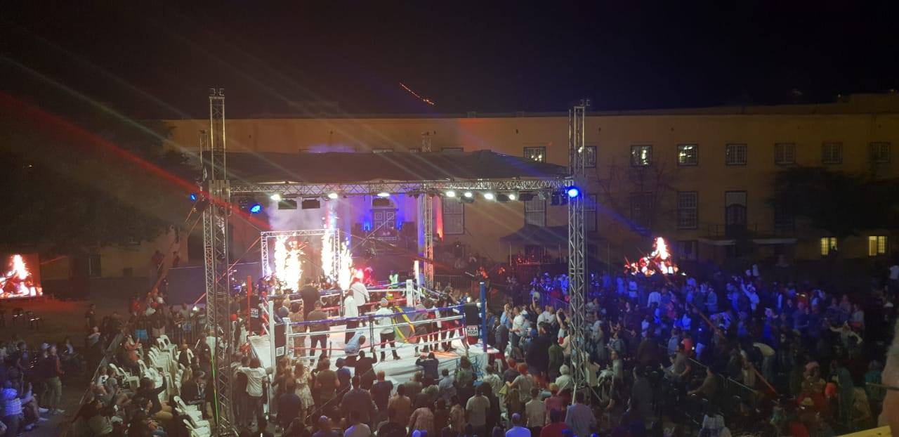 Outdoor boxing event setup with crowd and stage lights