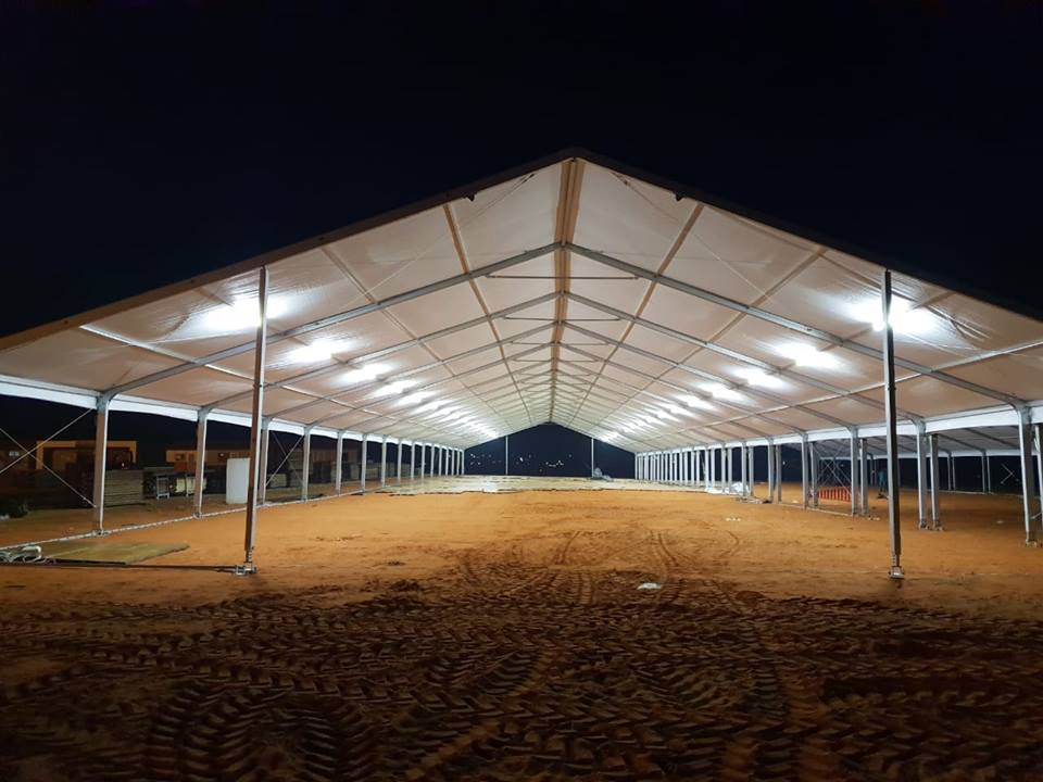 Large outdoor tent structure with lighting in a sandy area