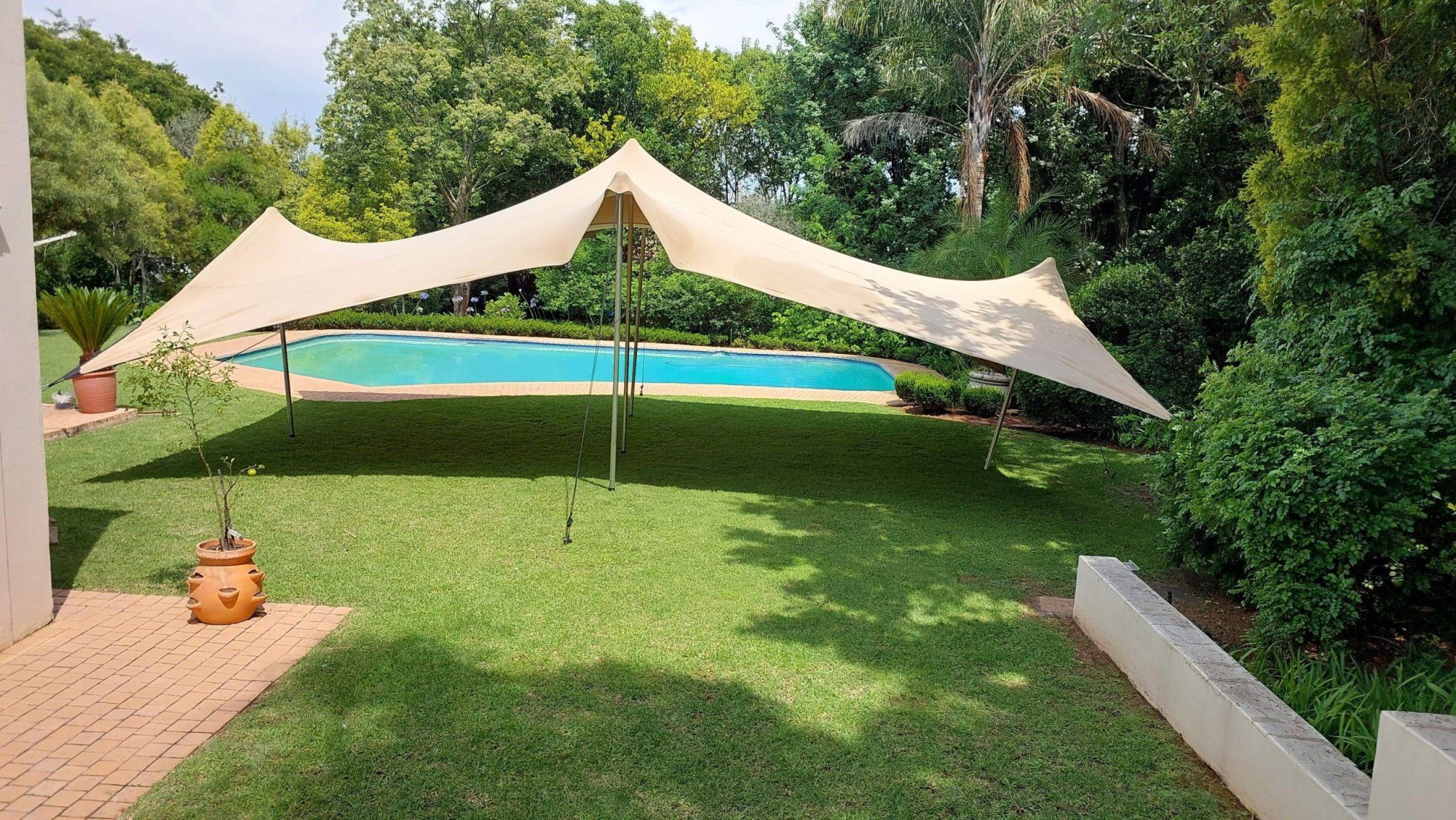 Stretch tent set up in a garden by a pool
