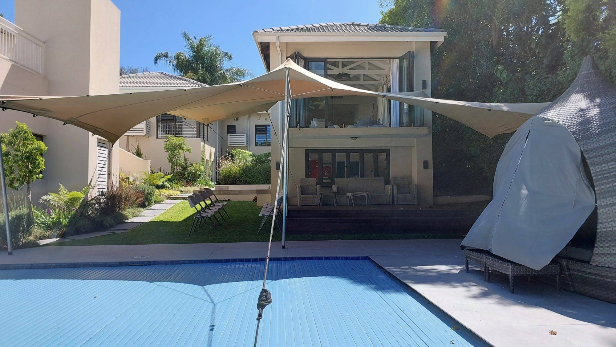 Stretch tent next to a pool area with a garden