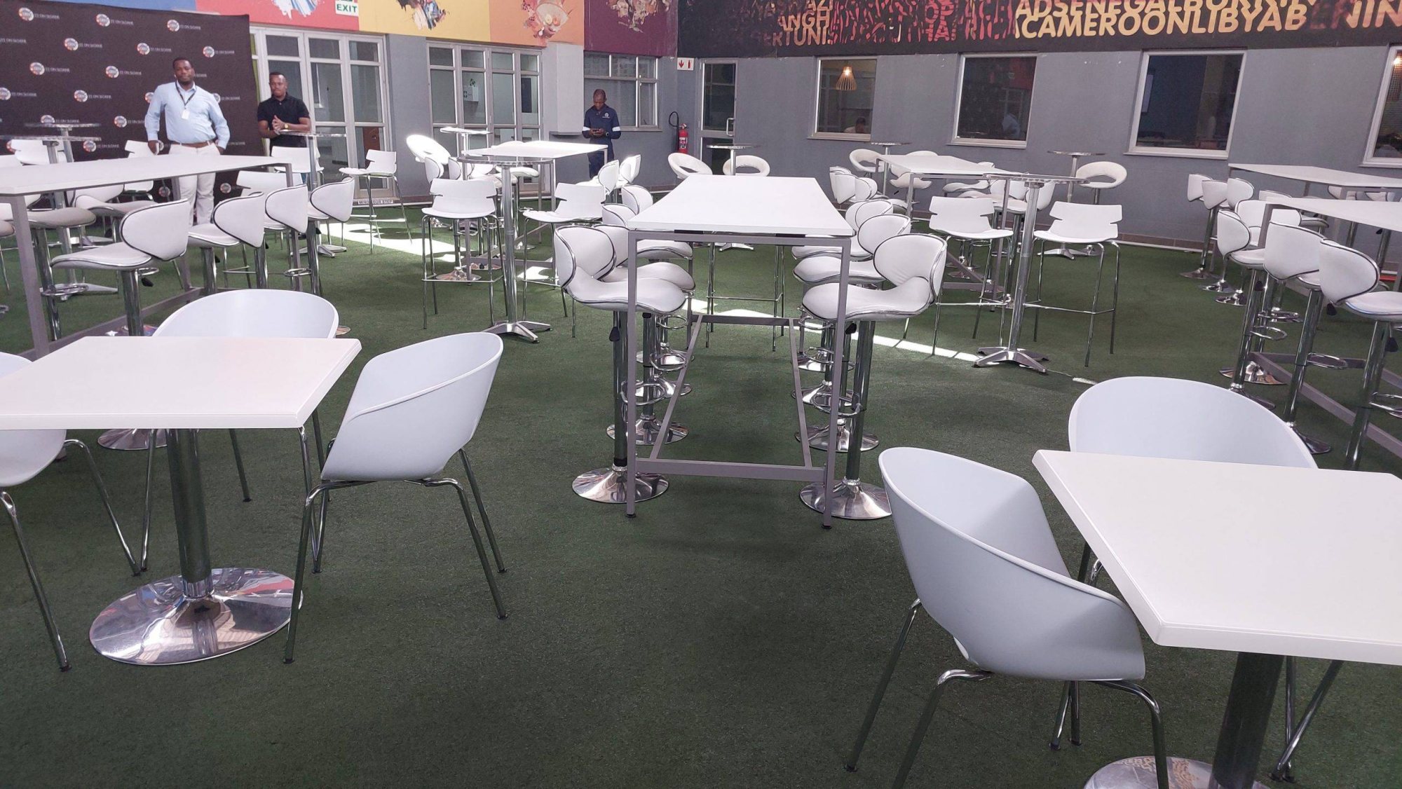 White cocktail tables and chairs set on green carpet.