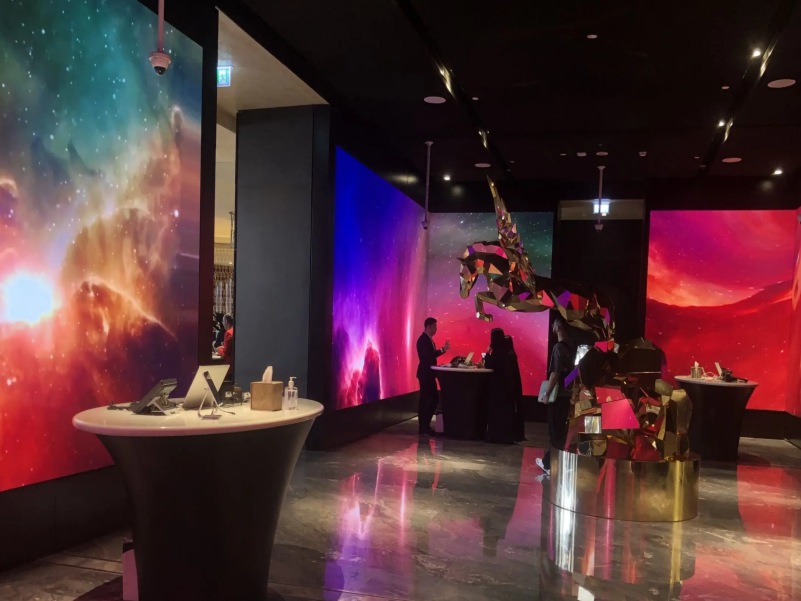 A large display of LED screens with vibrant visuals in a modern venue.