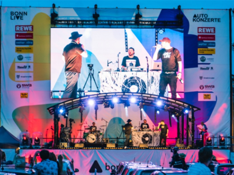 Large outdoor LED screen displaying a live concert performance