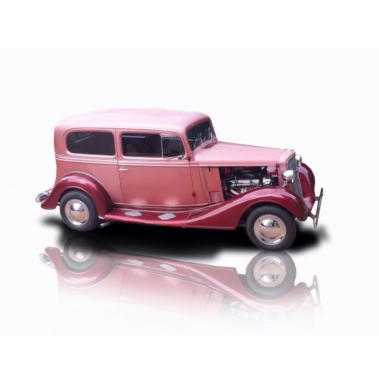 A restored vintage car in pink with shiny chrome details