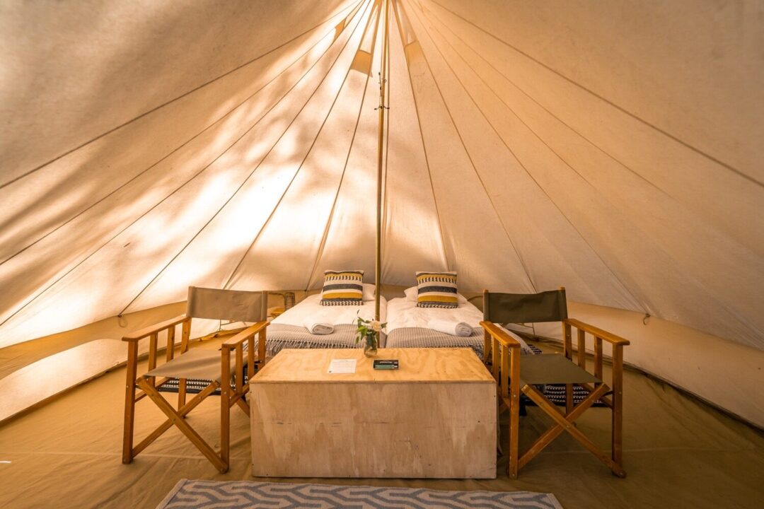 Interior of a spacious glamping tent with beds and seating