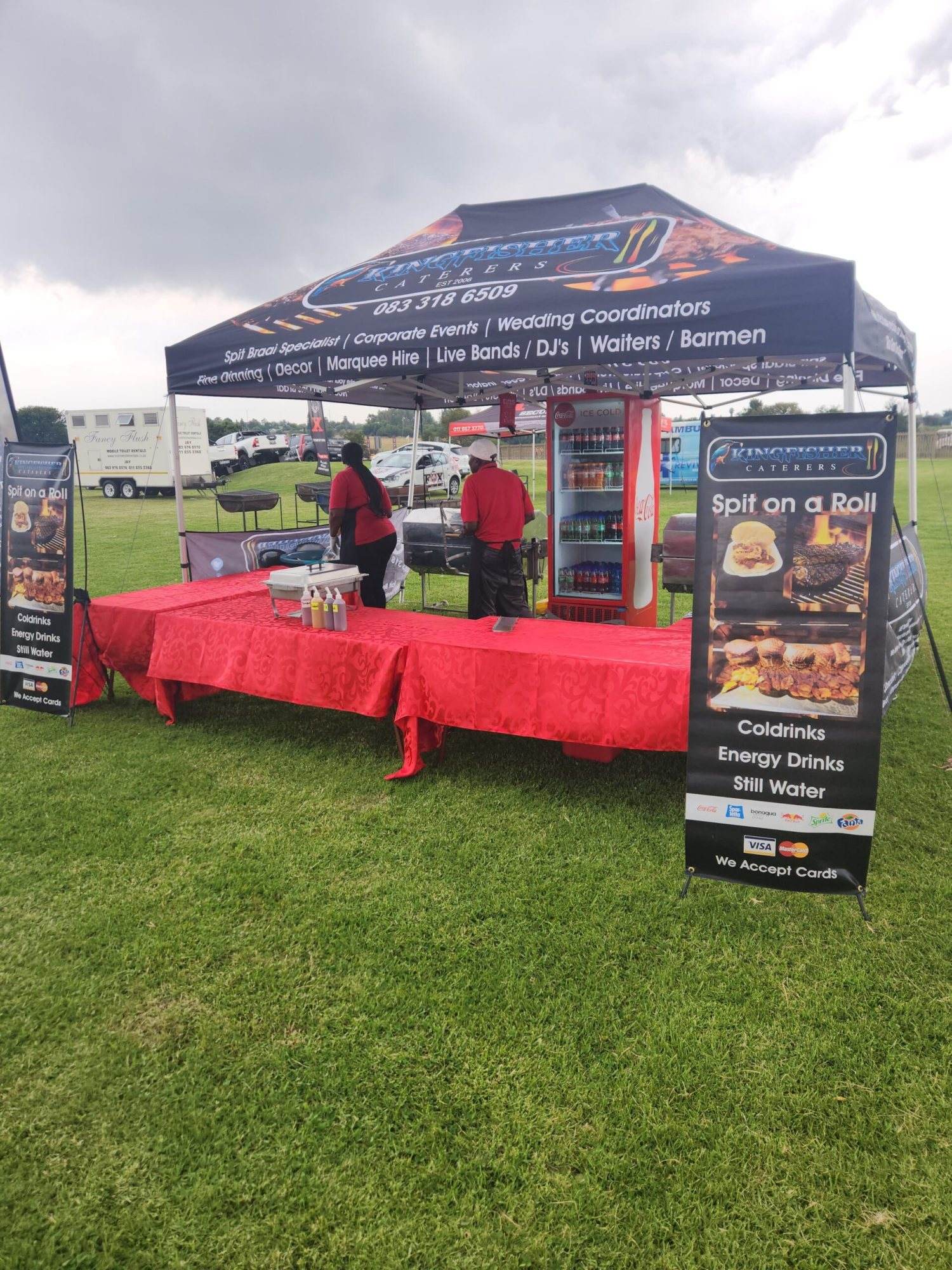 Catering booth featuring spit braai and drinks at an event