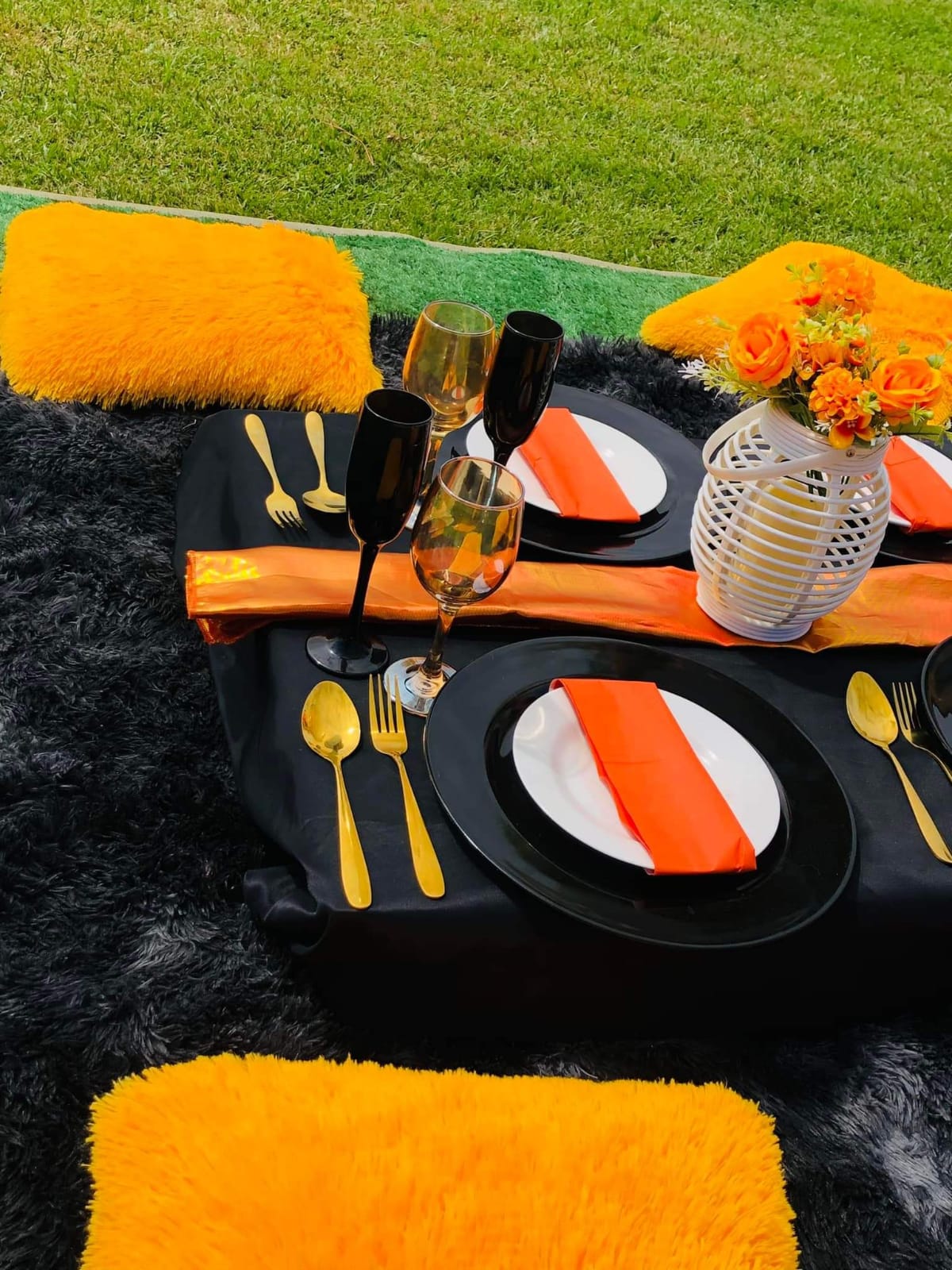 A picnic table with black tablecloth, orange accents, and floral decor