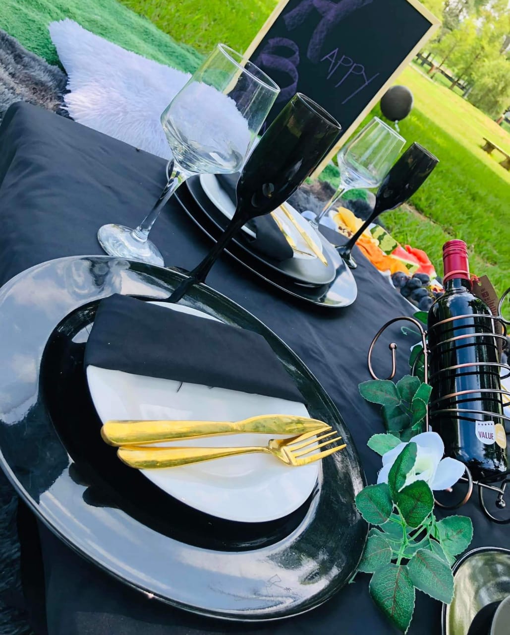 Black table setting with gold cutlery and wine