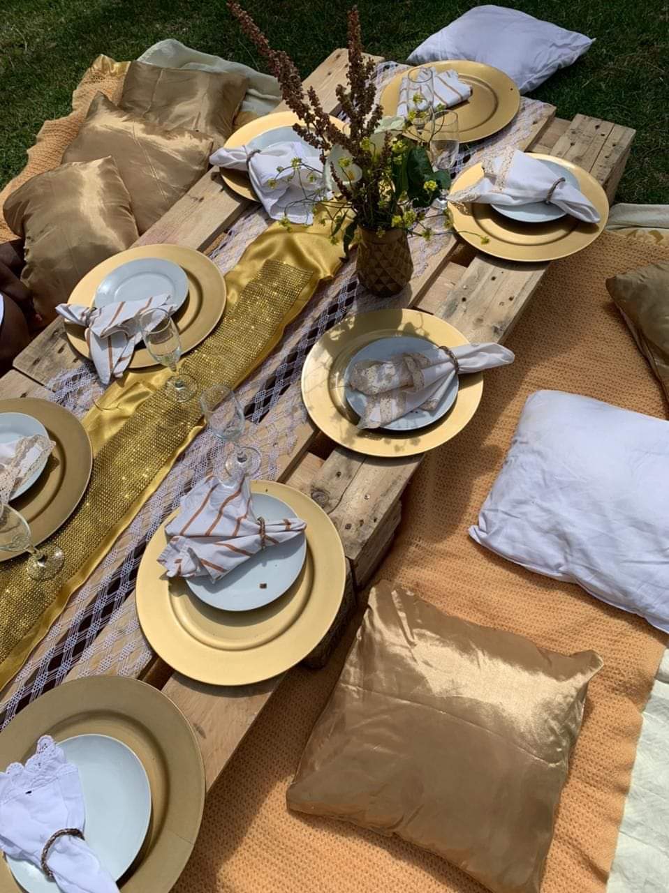 Table set with gold plates, cutlery, and decorative pillows