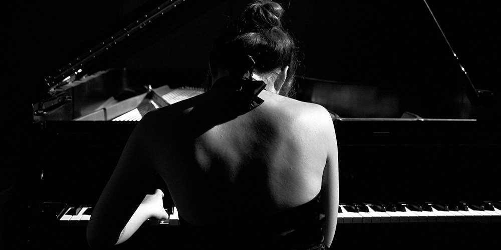 Fire dancer performing in front of a grand piano.