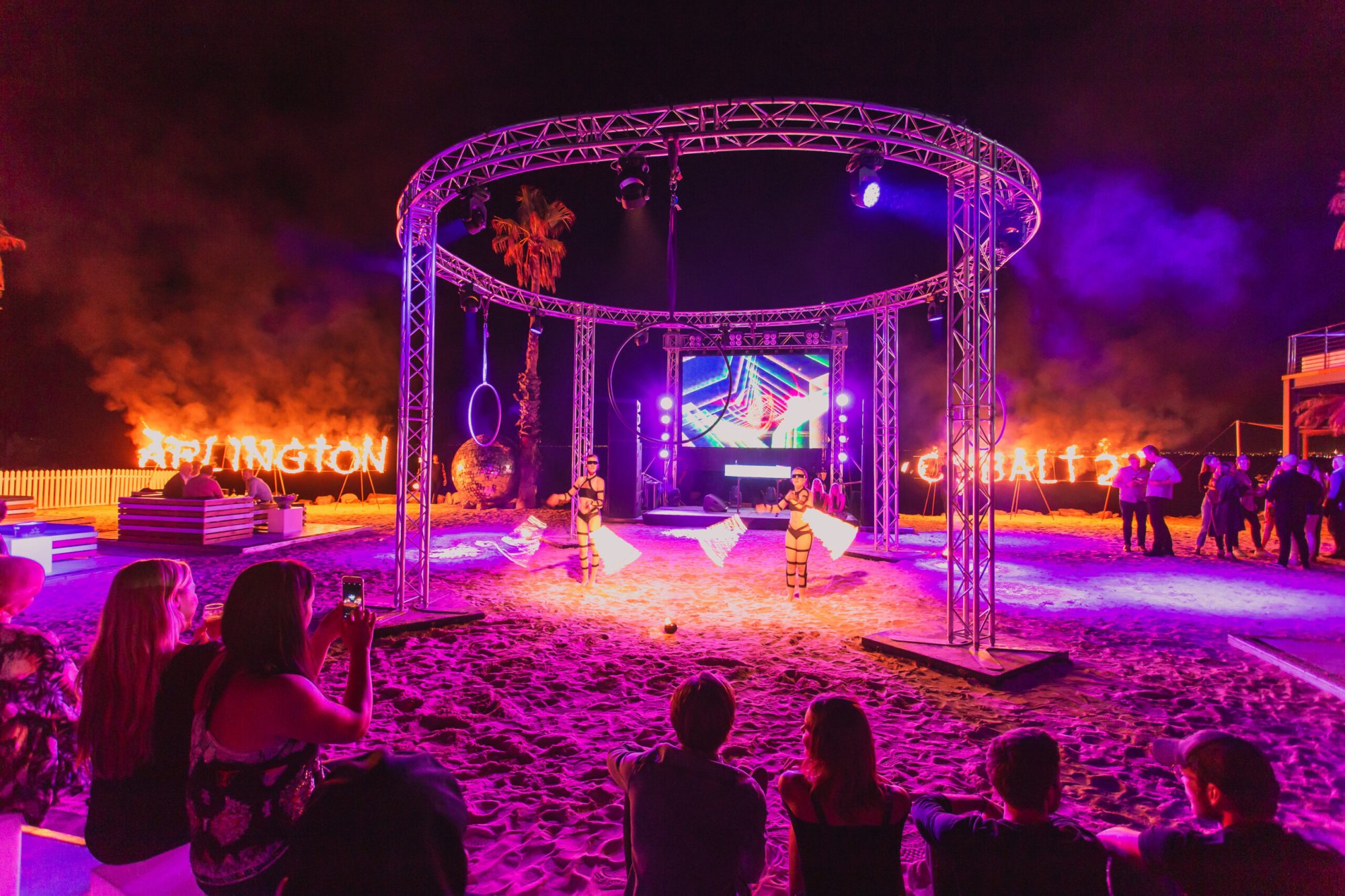 Fire dancers performing in a lit outdoor setting with an audience
