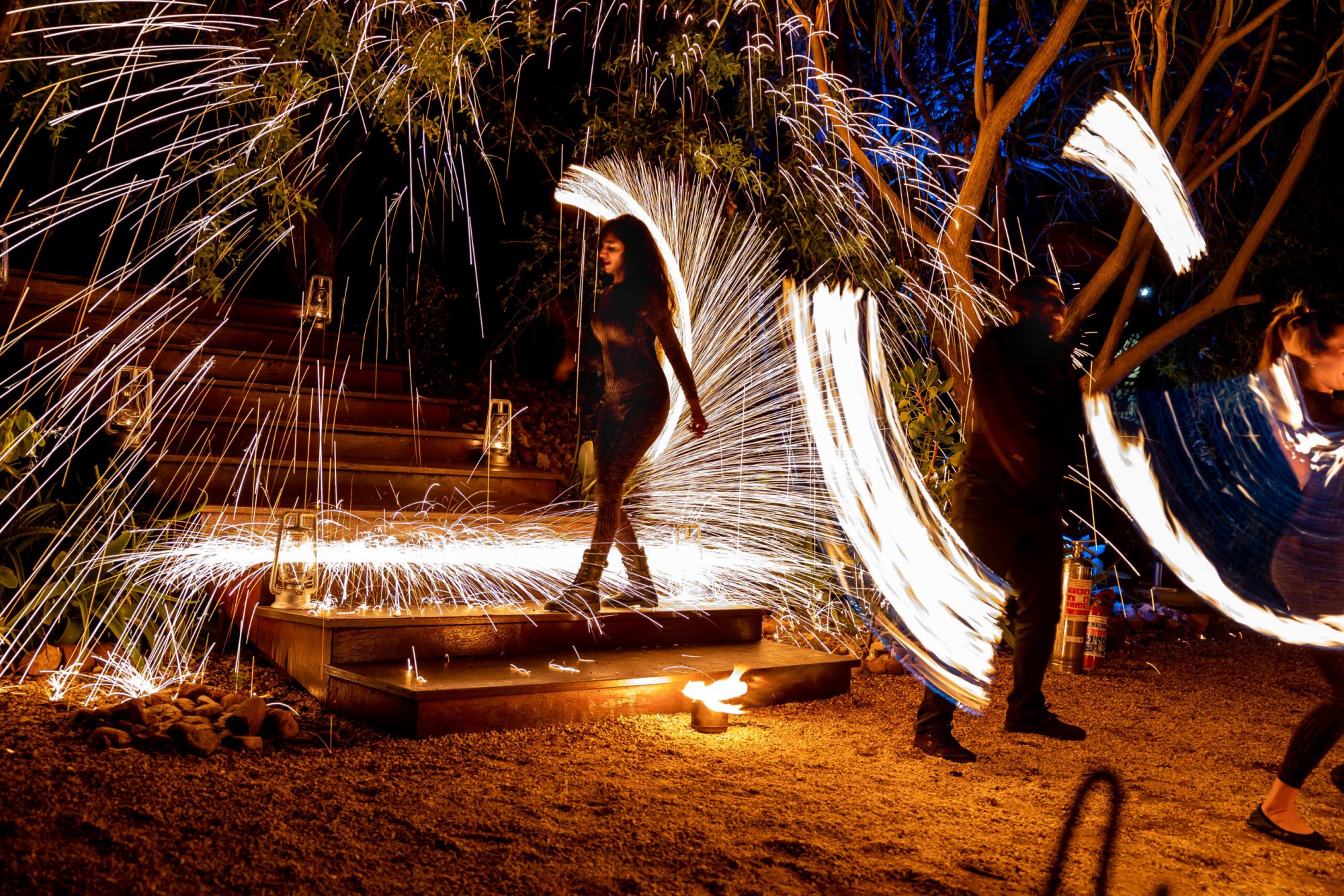 Performers creating fire trails in a night setting