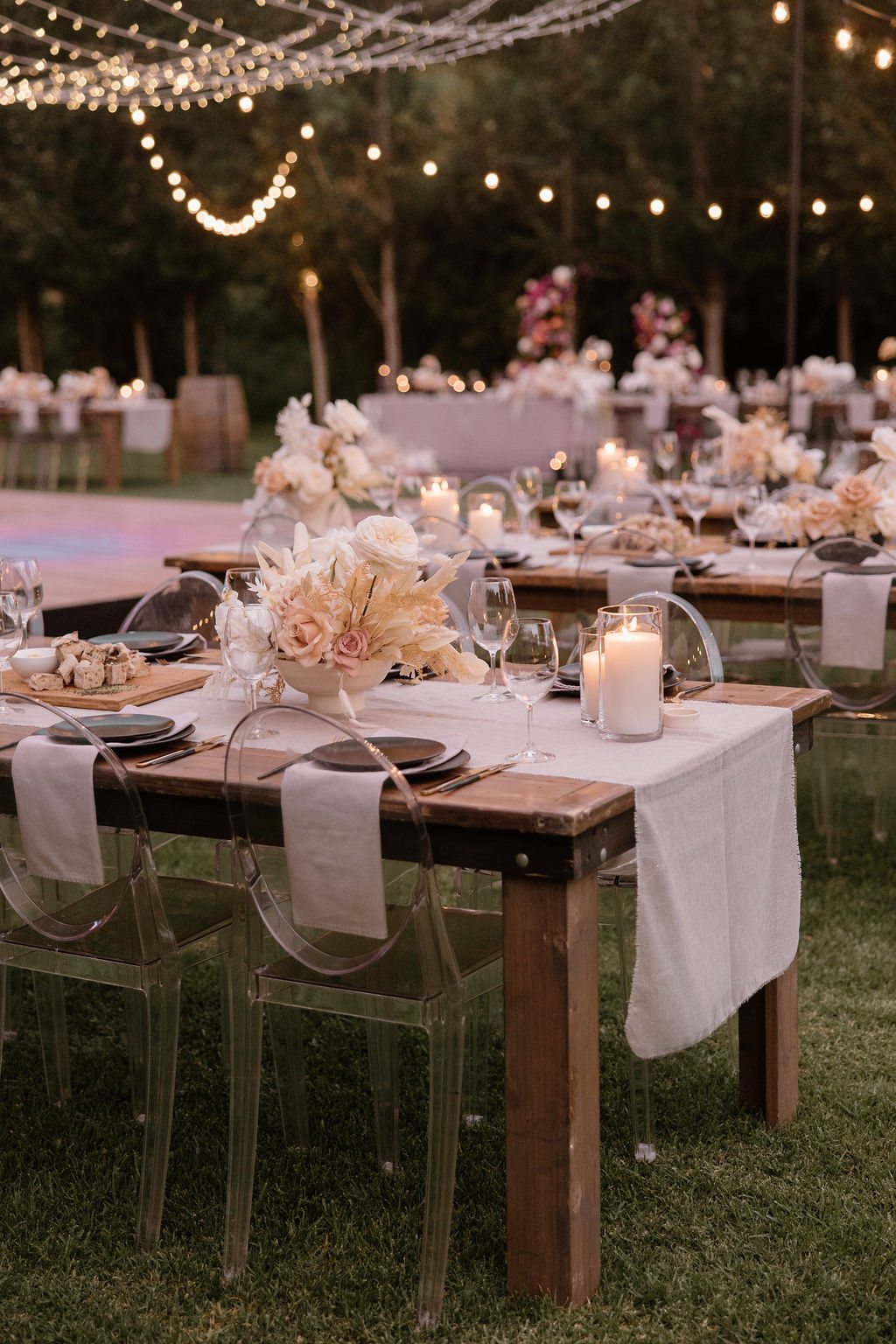 Outdoor dining setup with tables, candles, and flowers