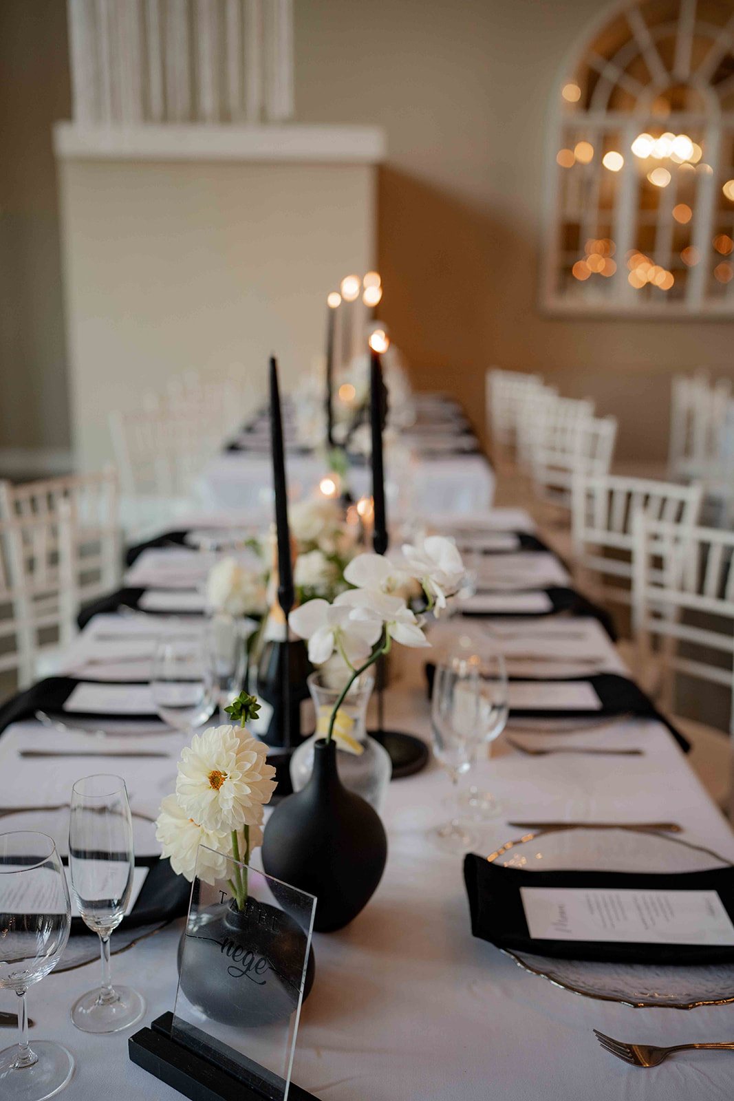 Dining table set with black and white decor and flowers.